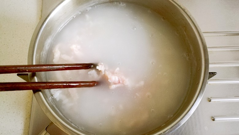 皮蛋瘦肉粥,将肉丝一条条放进米粥里,并划散。
