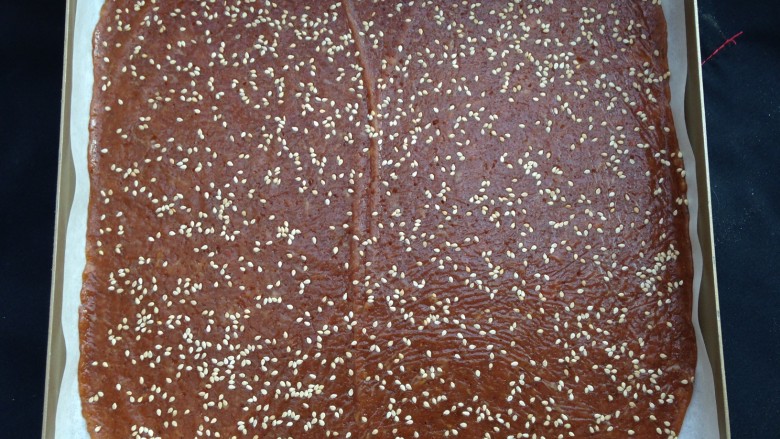 美味肉脯,擀均匀后,揭开保鲜膜,在上面撒上<a style='color:red;display:inline-block;' href='/shicai/ 678'>白芝麻</a>,然后盖上保鲜膜轻轻再擀一遍使芝麻粘进肉馅,最后揭去保鲜膜移入烤盘内