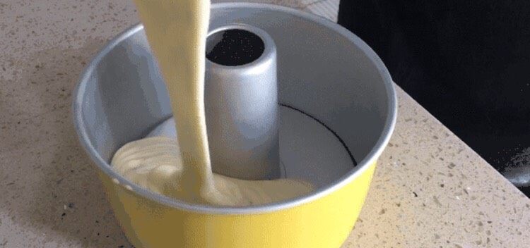 味淋香葱烟囱戚风蛋糕,将面糊倒入模具中。倒入的时候尽量保持30cm左右的高度,这样能够排出面糊中的大气泡。倒好后,拇指扣住烟囱,其他手指抓住模具边缘,上下震动几次,排出剩余的气泡。