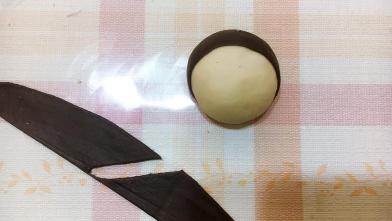 白雪公主与七矮人,将扁平状的深黑色可可粉面团包裹在胡萝卜面团上方。将另外一个深黑色可可粉面团擀成扁平状分割成两半,沾在胡萝卜面团上。