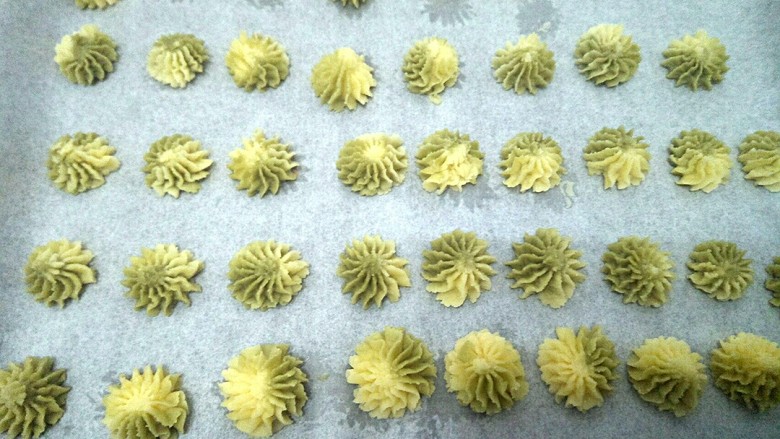 雪花双色曲奇,在垫有油纸的烤盘上挤出花型。刚挤时要稍微用力点,待手温将面团稍软化后就很好剂的。
