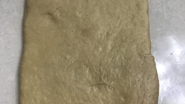 蜂蜜咖啡吐司,取一个面团小块的压在底下,用擀面杖擀成小长方形。