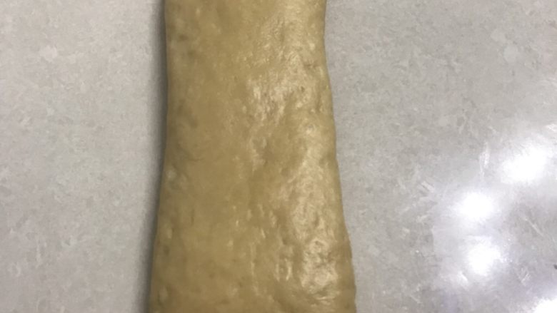 蜂蜜咖啡吐司,取一个长条面团,收口朝下先用手掌拍打排气。