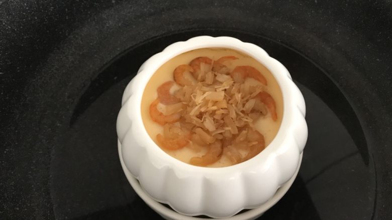 瑶柱虾米蒸水蛋,蒸至约5分钟,蛋液表面凝固时把炒香的瑶柱虾米放在上面,再盖上盖子蒸约10分钟