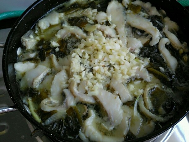 酸菜鱼,鱼熟后关火,把蒜粒撒上。