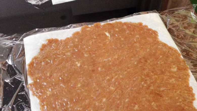 自己动手DIY美味肉脯,好吃得停不下来,在肉泥上面盖上保鲜膜,用擀面杖轻轻地擀,让肉泥尽量平,薄,面积尽可能地大,当然不能溢出厨房纸。