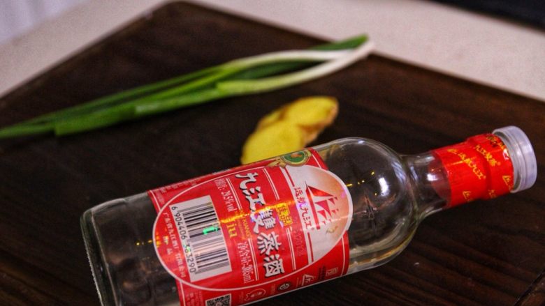 砂锅鱼头,②姜葱拍碎,放到手心里面,倒入白酒,混合成姜葱酒腌制鱼头。