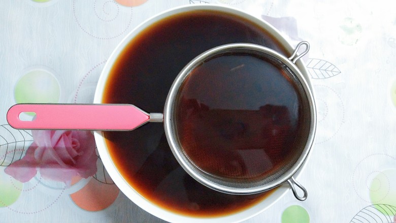 烧仙草红豆奶茶,准备好一个大碗和过滤网,把熬好的红茶倒入过滤网里,过滤掉茶叶!