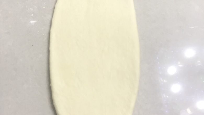 70%中种炼乳排包,取一个面团,收口朝上,用擀面杖从中间向二头擀成长舌形