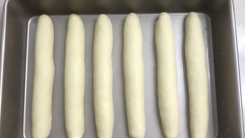 70%中种炼乳排包,以次用二手撑搓成和烤盘一样宽的长条,收口朝下整齐排列在烤盘中