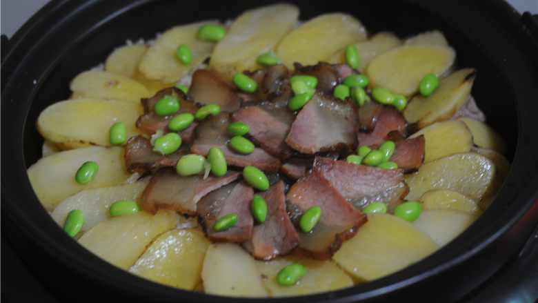 腊肉排骨放,将腊肉和排骨摆放在上面。盖上锅盖继续焖煮至完全熟透,撒上青豆粒即可。