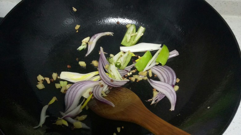 羊肉卷炒双菇,锅中放入适量油,放入洋葱、青椒、姜末快速翻炒。