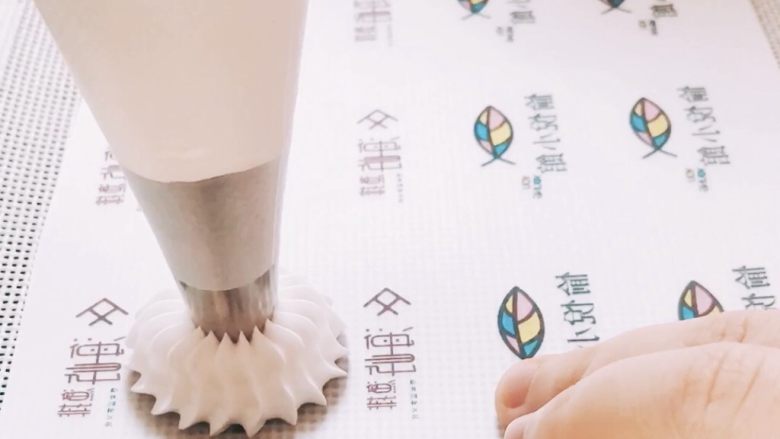 超高颜值转印蛋白糖马琳糖,拿出转印纸(建议底层加层硅胶垫使其受热均匀)放在烤盘上。塑料片朝下,糖面朝上(请大家不要妄想着把塑料片撕下,蟹蟹),小吾用的是18齿中号裱花嘴,用均匀的力道在图案上挤出糖霜即可。在这里想说的是,手不要发抖啊,距离糖纸一定高度挤出糖霜,快速将裱花袋垂直一提就能挤出漂亮的糖霜啦~(其实我也没挤得很漂亮,哈哈哈)