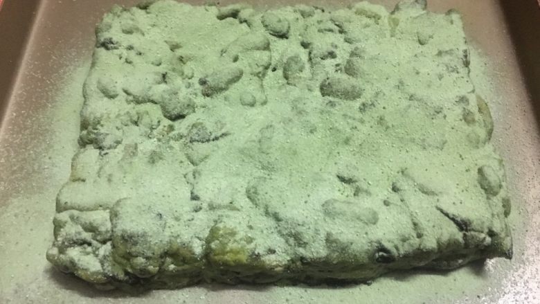 奥利奥抹茶雪花酥,放入平盘中压紧成正方形,抹茶粉跟奶粉混合后撒到表面上