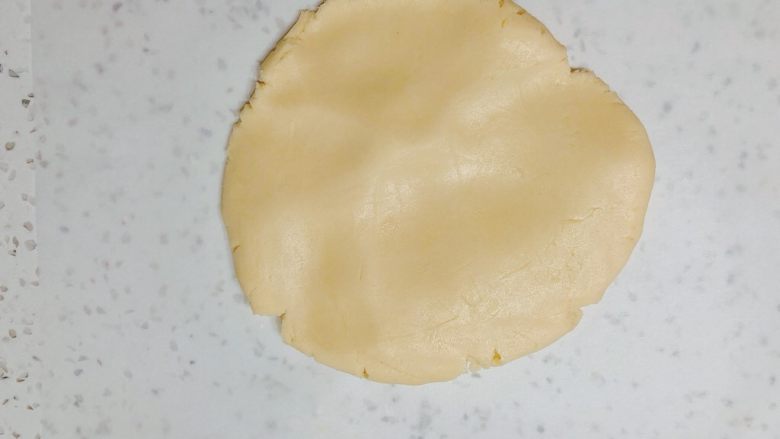 超平整口感佳的糖霜饼干底,台面垫一张油纸,把饼干面团放在上面,先用手掌按平一些。