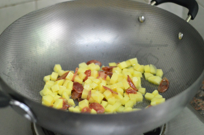 土豆腊肠焖饭,锅里烧热油,依次放入腊肠、土豆拌炒