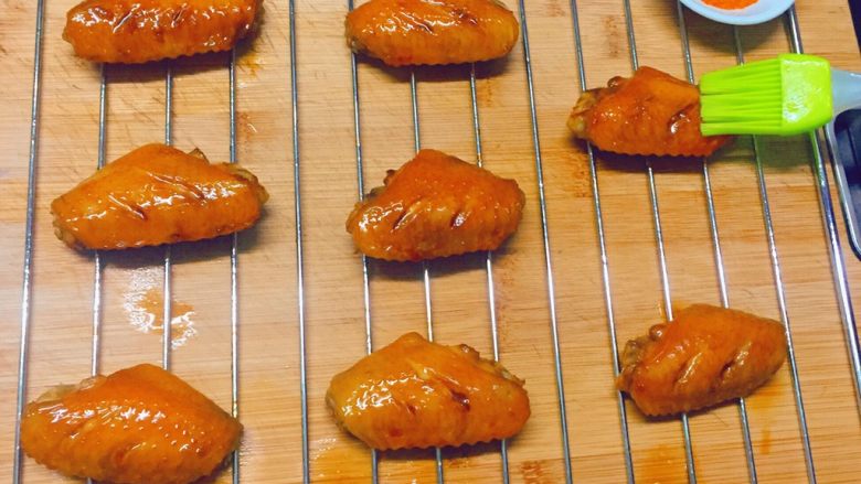 美味烤鸡翅,10分钟后,戴上烤箱专用手套,取出烤网,先在鸡翅上刷一层油,再撒上香辣孜然调味粉。然后将烤网再次放入烤箱中层,上下火210度烤10分钟即可出炉。