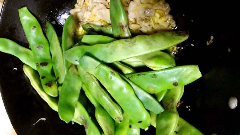 猫厨物语-蒜香油豆角,把肉用锅铲扒到一边。下前面焙干水分的豆角翻炒。(现在告诉你们为什么豆角要先炒一下。第一是为了这一步不会油遇水崩的一塌糊涂。第二是为了更好的让豆角入味)