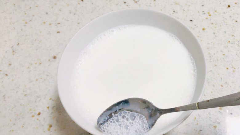蜜豆双皮奶,牛奶加热几分钟后,倒入碗中,拂去上面的泡沫,静止产生牛皮
