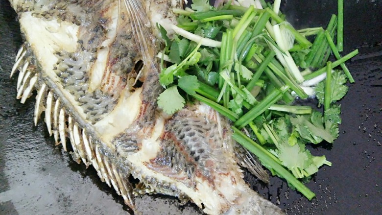 香煎罗非鱼,罗非鱼煎好后往旁边移然后弄剩一点油再放入蒜头,葱和香菜炒一下