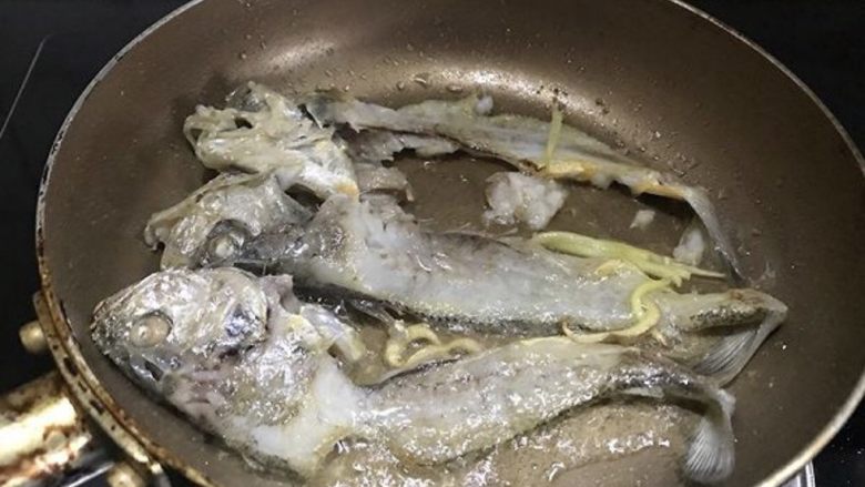 咸菜黄鱼面,取一小锅,倒少许油,加姜丝,把鱼骨放进去煎一煎