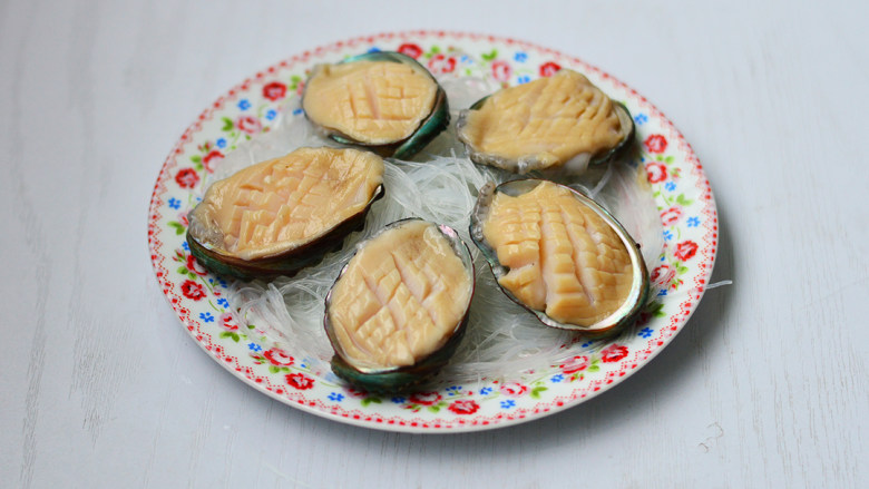 蒜蓉粉丝蒸鲍鱼,将鲍鱼肉放入鲍鱼壳里,摆上摆入粉丝碗中