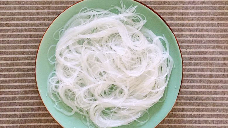 金针菇粉丝蒸虾仁,将泡好的粉丝沥水剪成对半(因为粉丝太长了),铺在盘底。