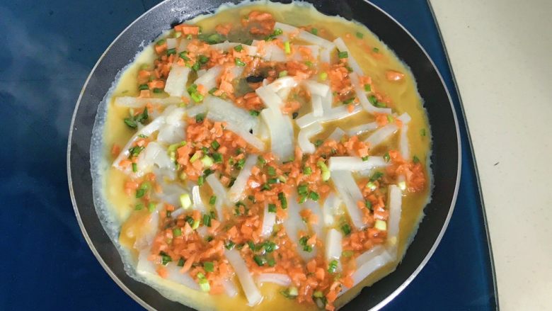 年糕鸡蛋饼,慢慢转动锅子,使蛋液均匀分布在年糕周围