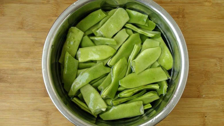 宽扁豆炒麻辣香肠,宽扁豆洗净后用手掰成3至4厘米大小,在清水中浸泡15分钟。