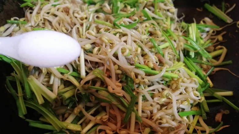 翡翠豆芽炒蒜苗,放入两小勺盐,翻炒几下。
