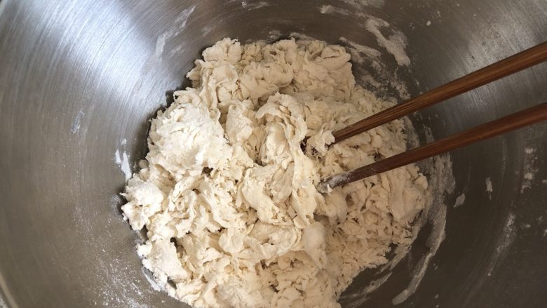 手工韭菜鸡蛋饺子,面粉加2g盐,一边倒入清水一边搅拌,成棉絮状