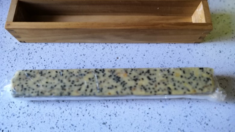 黑芝麻核桃咸味曲奇,用保鲜膜将面团包好放入模具里整形,整好后放冰箱冷冻一小时。