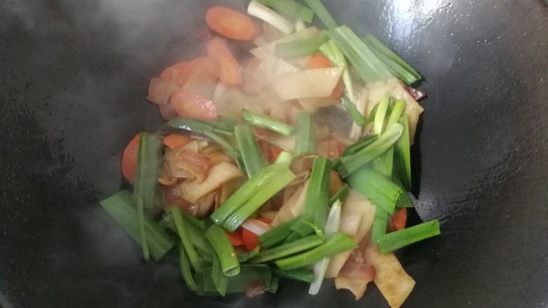 腊肉炒土豆饼,接着下入蒜青翻炒均匀；