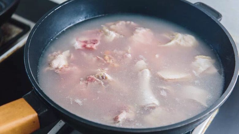 迎春聚宝盆,鸡肉与猪骨冷水下锅,煮沸待用,捞出用水冲洗干净
