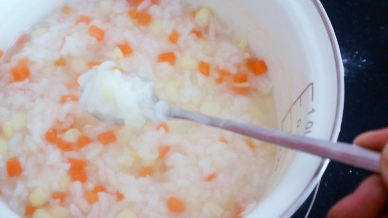 宝宝辅食之玉米胡萝卜粥,粥变得粘稠了,水份也明显减少了,米粒也都打开了这样就差不多好了,在熬几分钟就可以了