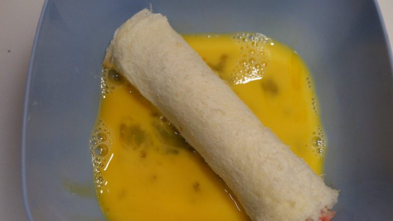快手早餐—香肠吐司卷,将吐司卷放在蛋液里,均匀的裹粘上鸡蛋液