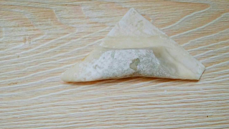 滚筒砂锅酱肉西蓝花馄饨,然后手指沾水,擦在折好的馄饨皮上。