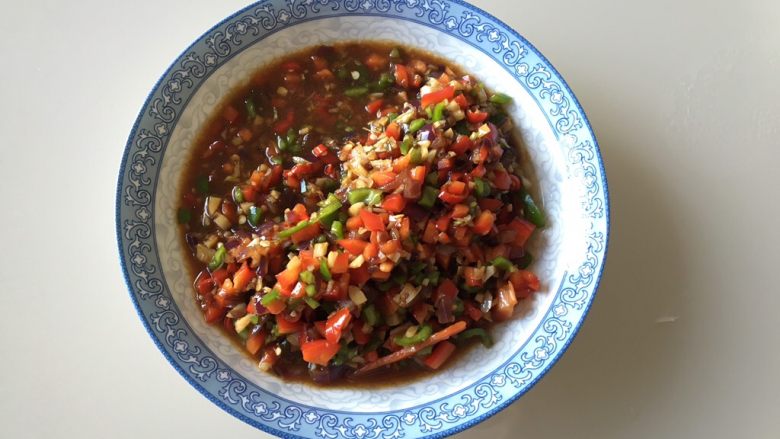 蒜香烤茄子,把青椒、红椒、小米辣丁和翻炒好的佐料拌匀,可尝一下味道,咸味要比平时炒菜咸一点儿,因为要用来烤茄子