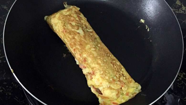 宝宝辅食之虾仁蔬菜厚蛋烧,12.蛋液表面凝固后再次卷起,小火煎至熟透。