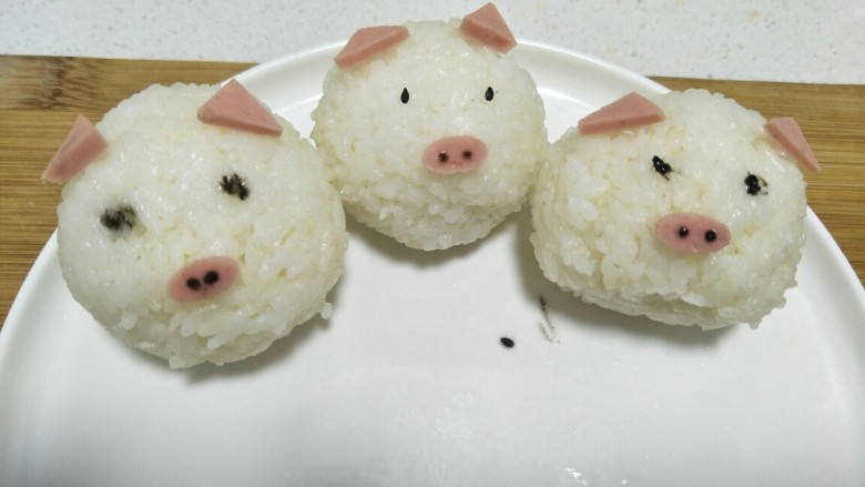 三只小猪~童趣鸡肉咖喱饭,<a style='color:red;display:inline-block;' href='/shicai/ 507'>米饭</a>用保鲜膜握成三个饭团,火腿做小猪的耳朵和鼻子,点黑芝麻酱或者黑芝麻当眼睛,鼻孔也点黑芝麻酱。