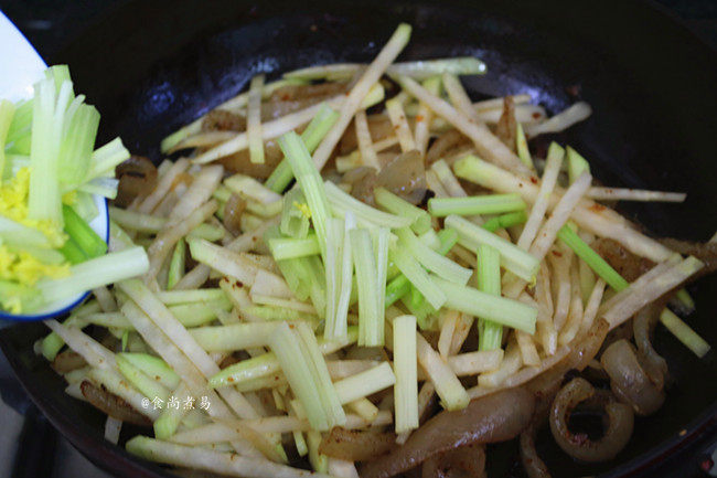 猪皮炒大头菜,倒入大头菜、芹菜继续煸炒;