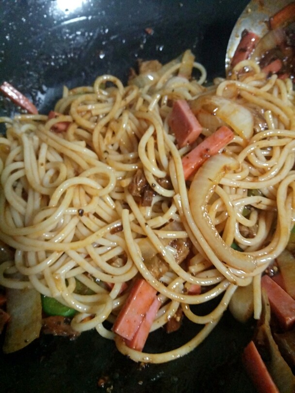 黑椒牛肉意面,然后我们继续再把主角意面以及适量的火腿(可省略)放入锅中炒制。