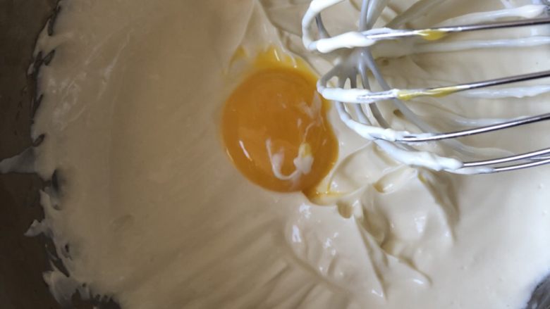 轻乳酪蛋糕cheese cake,接着蛋黄跟三次加入奶酪糊中,搅拌均匀,每次都充分搅拌均匀后再加入下一个。
