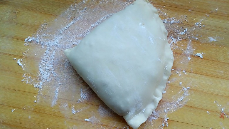 牛肉饼,再折下来,成了一个三角状,把所有空白边都捏合,这样就不会露馅了。
