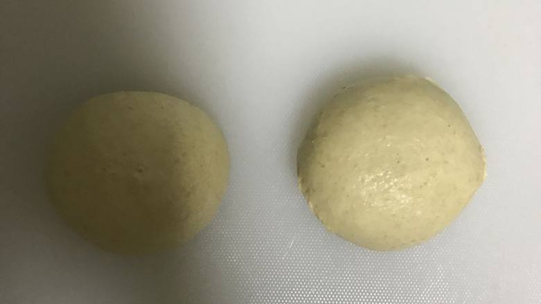 全麦豆沙麻薯肉松软欧面包,取出按压排气,平均分成2份滚圆,盖上保鲜膜松弛10分钟。