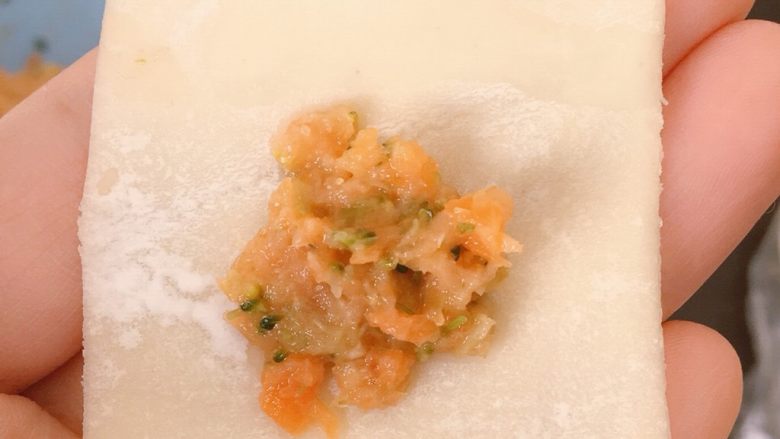 胡萝卜西兰花蛋黄猪肉小馄饨,第二种包法:取适量馅料放在饺子皮上(同样的不要太多哦),然后在上面空白部分沾一点清水