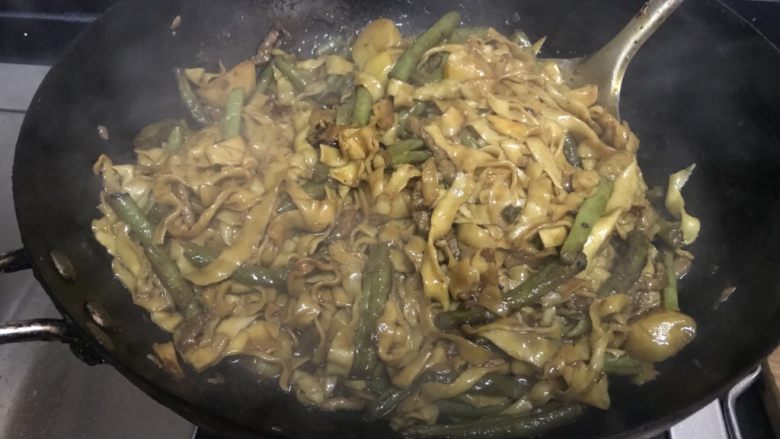 衩姐秘制豆角焖面,这一次,等锅里的汁焖到只剩1/5的时候,打开锅,撒上葱花,用筷子把面条一一挑散,然后把锅里的一切拌匀,让所有食材都均匀地裹上料汁。(建议你用不粘锅或铸铁锅做焖面)
此刻,土豆应该已经彻底焖烂,搅拌的时候会让土豆沙裹满面条。