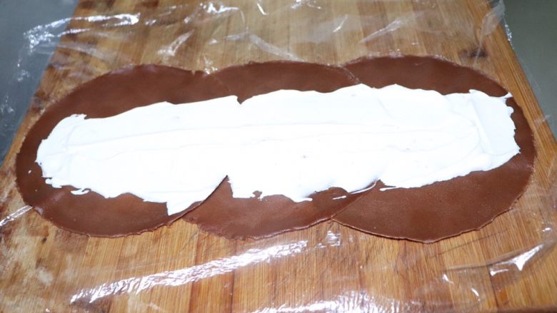 网红毛巾卷,面包上铺一层保鲜膜,放上两到三张饼皮,一张叠一张的铺开,奶油从中间位置抹平。