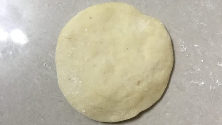 桑葚烫种小餐包,取一个面团用手掌拍扁,边上稍薄,尽量圆一些。