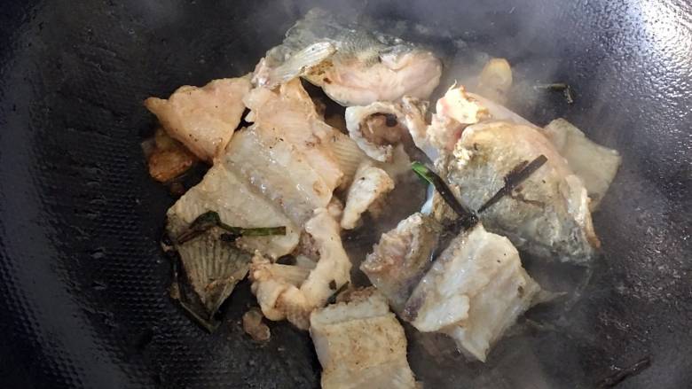 蒜苗萝卜鲈鱼汤, 鱼骨下油锅,翻炒;加入料酒,煸炒至鱼肉变色;